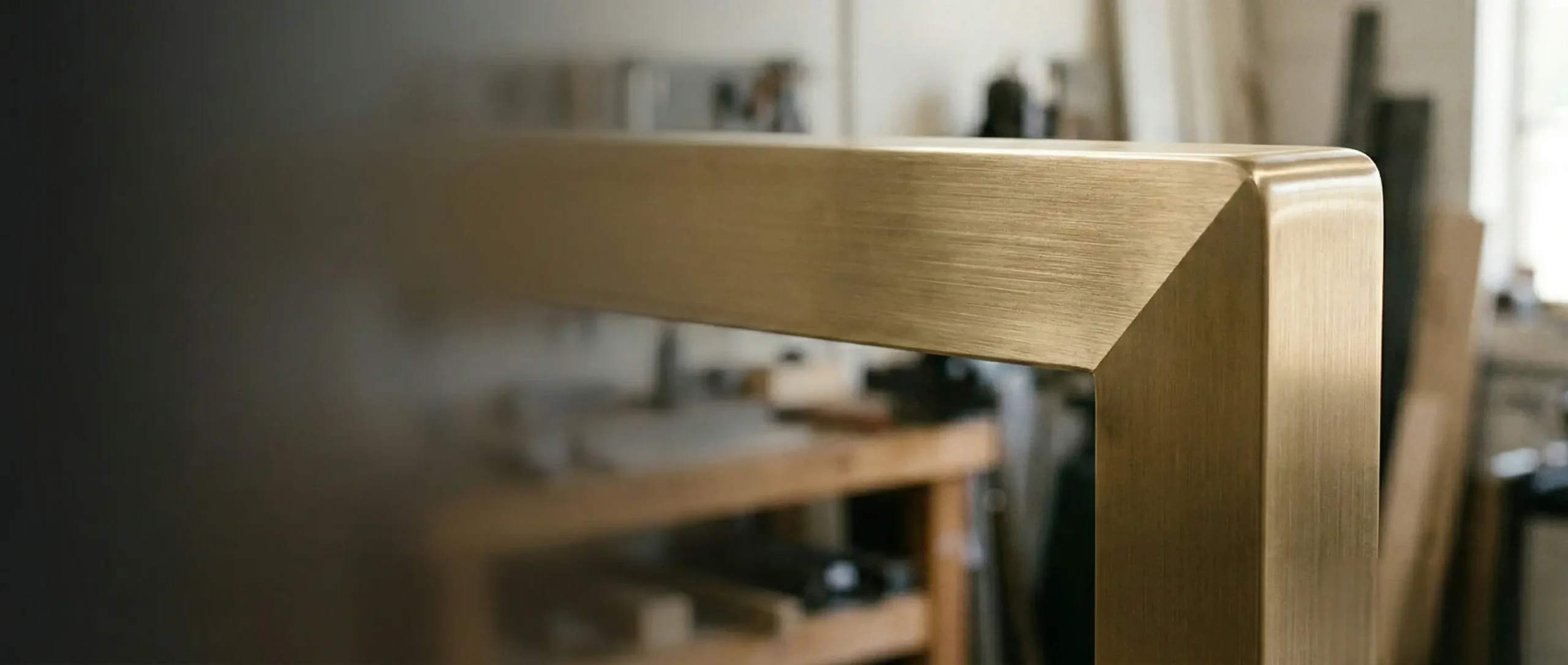 Close-up of a brushed brass portal corner with a controlled satin sheen, finished on solid metal for architectural metalwork.