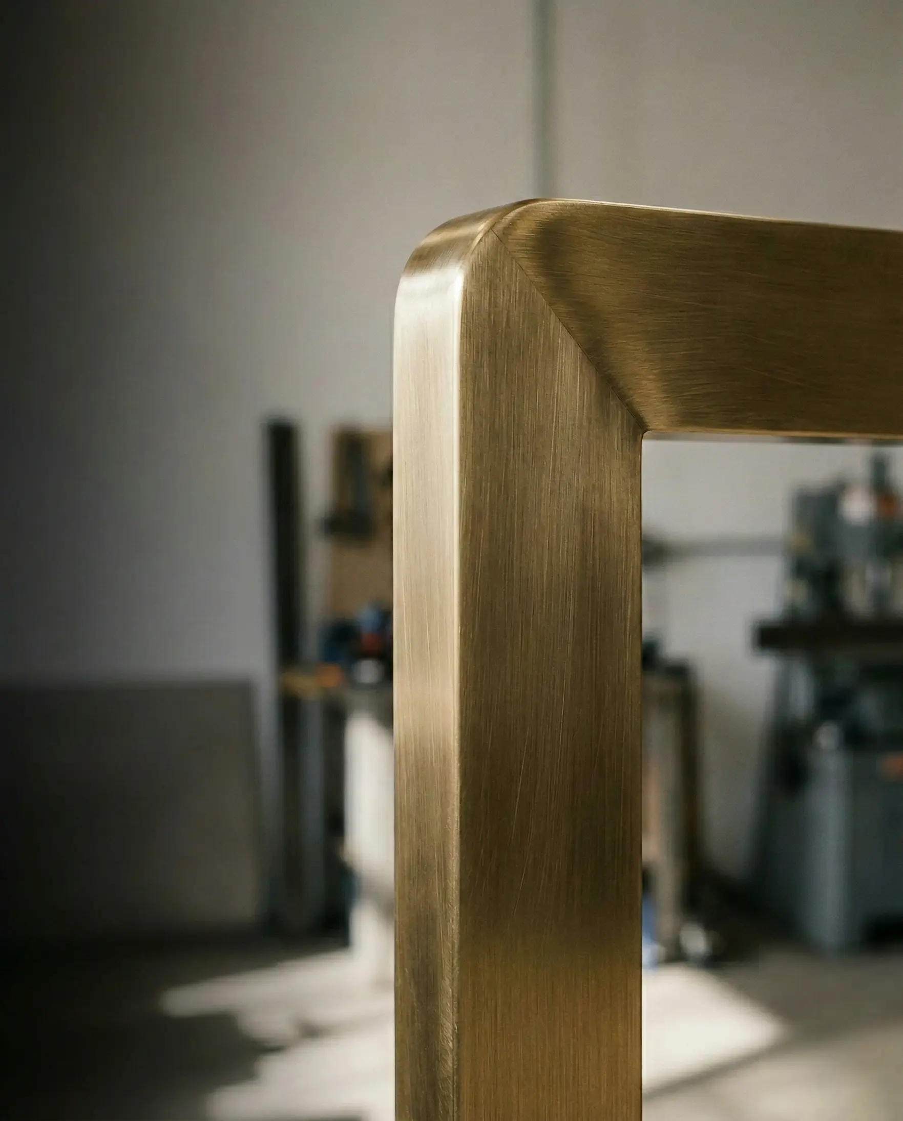 Close-up of a brushed brass portal corner with a controlled satin sheen, finished on solid metal for architectural metalwork.