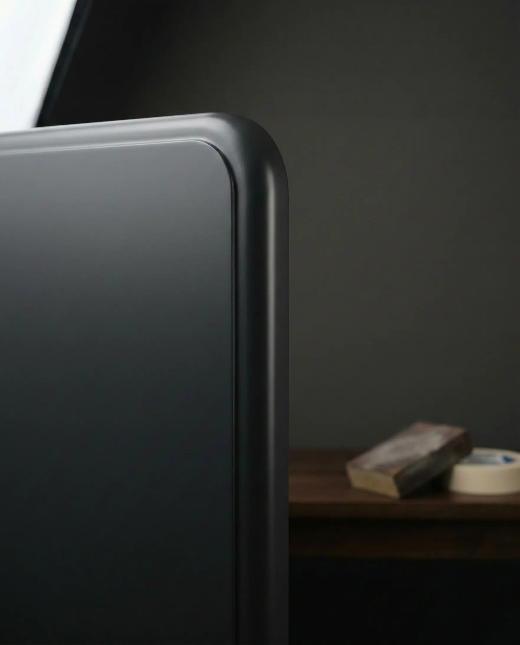 Close up of a satin wet coating finish on a radiused MDF edge, with a sanding pad blurred in the background.